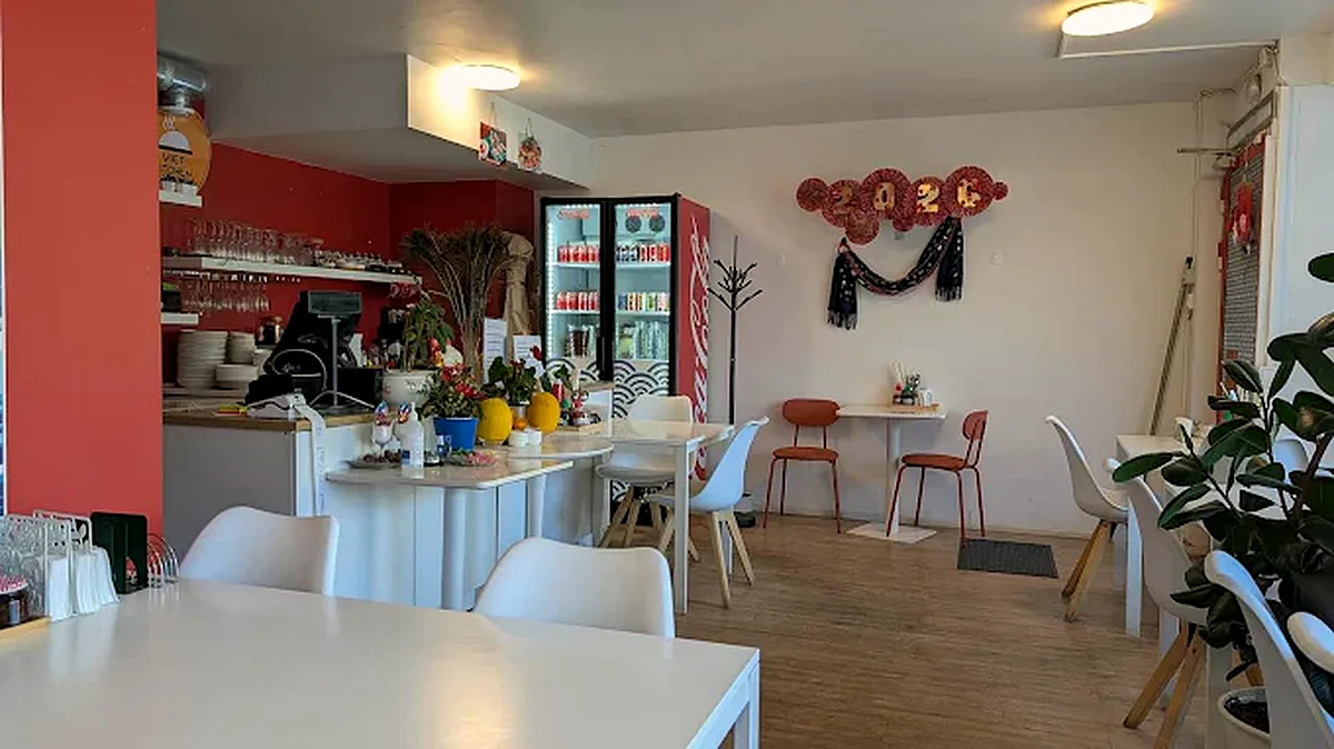 Viet Kitchenin valoisa sali: valkoiset pöydät, punainen seinä ja viherkasveja